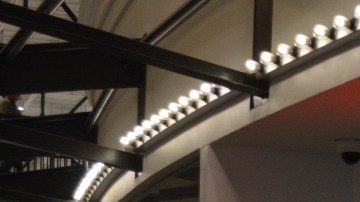 Imagen de una sala de cines de la cadena AMC, en la que se ve una zona para comprar boletos indicada con letras de color rojo.