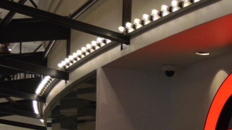 Imagen de una sala de cines de la cadena AMC, en la que se ve una zona para comprar boletos indicada con letras de color rojo.