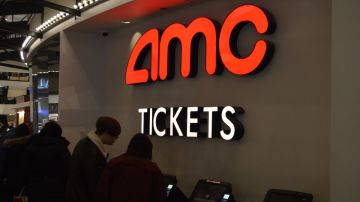 Imagen de una sala de cines de la cadena AMC, en la que se ve una zona para comprar boletos indicada con letras de color rojo.