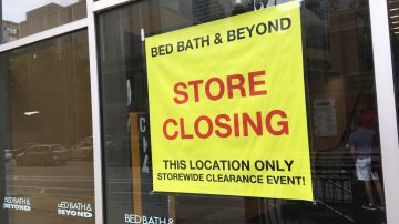 Imagen de un letrero de color amarillo con letras rojas en el que se lee sobre el cierre de una tienda de la marca Bed Bath & Beyond.