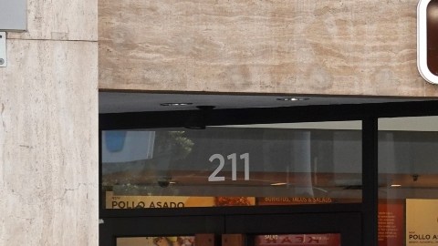 Imagen de un restaurante de la cadena Chipotle y afuera una persona con una chamarra azul que sostiene una bolsa.