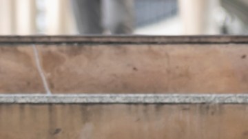 Imagen de una persona que está sentada en unos escalones con la mano en el rostro.