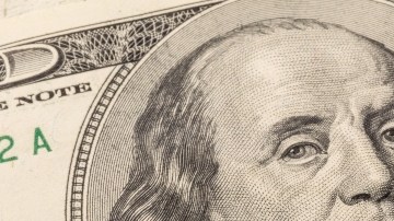 Imagen de un cheque de reembolso de impuestos y de varios billetes de $100 dólares.