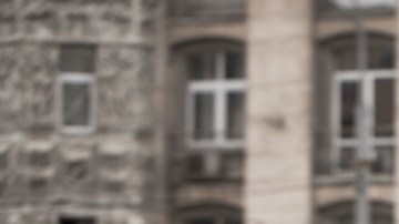 Imagen de una persona con una gabardina café que camina por la calle.