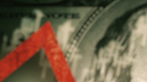Imagen de un billete de $100 dólares cruzado por una flecha de color rojo que marca una tendencia a la baja.