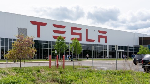 Imagen de una fábrica de Tesla frente a un jardín.
