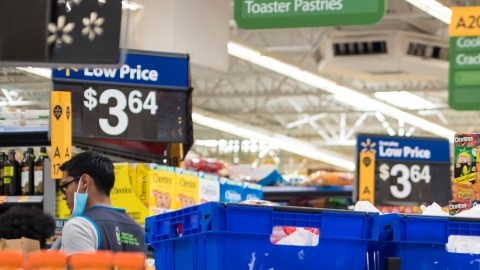 Imagen de varias personas que caminan por pasillos de una tienda de Walmart.
