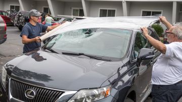 YARMOUTH, MA - JULY 23: Men put plastic over the windshield of a car that was damaged after a tornado touched down on July 23, 2019 in Yarmouth, Massachusetts. A rare tornado brought 80 mph winds to parts coastal Massachusetts, severely damaging a popular hotel and other nearby properties. (Photo by Scott Eisen/Getty Images)