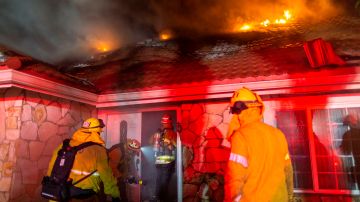 Firefighters enter a burning house as they fight the Saddleridge Fire in the Porter Ranch section of Los Angeles, California, early October 11, 2019, - The fire broke out late October 10 and has scorched some 4,600 acres (1,816 hectares), and forced mandatory evacuation orders for 12,700 homes. (Photo by DAVID MCNEW / AFP) (Photo by DAVID MCNEW/AFP via Getty Images)