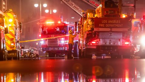 Firefighters gather near firetrucks after a fire in a single-story commercial building sparked an explosion in the Toy District of downtown Los Angeles on May 16, 2020. - At least 11 firefighters were injured in downtown Los Angeles when a fire in a commercial building sparked a major explosion and spread to nearby structures, fire officials said. Some 230 responders battled the blaze as it spread to other buildings in the area before it was extinguished around two hours after it began. (Photo by Apu GOMES / AFP) (Photo by APU GOMES/AFP via Getty Images)