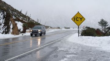An SUV drives past an icy sign in the San Gabriel Mountains in the Angeles National Forest, California, on February 24, 2023. - Californians more used to flip flops and shorts were wrapping up warm Thursday as a rare winter blizzard, the first in more than 30 years, loomed over Los Angeles, even as the US East Coast basked in summer-like temperatures. (Photo by Allison Dinner / AFP) (Photo by ALLISON DINNER/AFP via Getty Images)