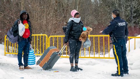 Un oficial habla con migrantes que llegan a Canadá por Roxham Road en Roxham, Quebec.