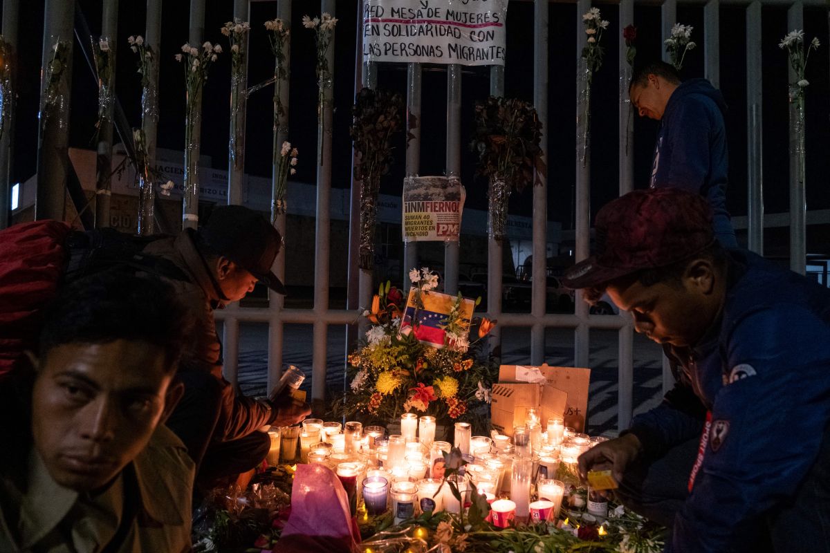 Los migrantes encienden velas durante una vigilia frente a las instalaciones de inmigración mexicanas donde al menos 38 migrantes murieron en un incendio, en Ciudad Juárez, estado de Chihuahua, el 28 de marzo de 2023, México.