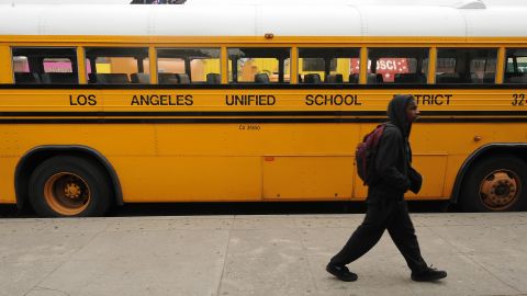 A student on his way to school walks past a Los Angeles Unified School District (LAUSD) school, in Los Angeles, California on February 13, 2009. California Governor Arnold Schwarzenegger has threatened to send layoff warnings to at least 20,000 state workers unless a budget agreement is reached Friday. AFP PHOTO/ ROBYN BECK (Photo credit should read ROBYN BECK/AFP via Getty Images)