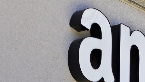 Imagen de un logotipo de Amazon colocado sobre el muro de un edificio de color gris.