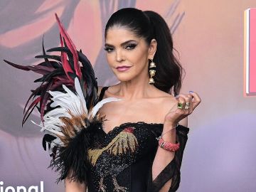 Ana Bárbara posa de rodillas en la playa, usando un bikini estampado