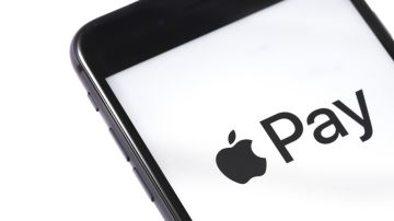 Imagen de un teléfono iPhone en cuya pantalla en color blanco de se ve una manzana de color negra y la palabra Pay.