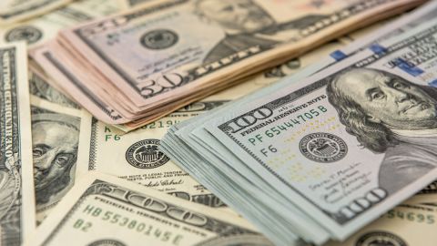 Imagen de varios fajos de billetes de dólar, unos colocados sobre otros.