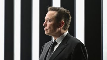 Imagen de Elon Musk parado de perfil mientras viste un traje de color negro.