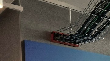 Imagen de una oficina con mamparas de varios colores que tienen el logotipo de la empresa Meta. También se ven a dos personas sentadas.