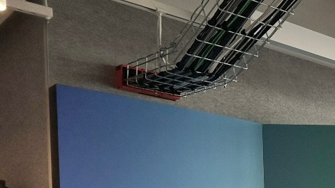 Imagen de una oficina con mamparas de varios colores que tienen el logotipo de la empresa Meta. También se ven a dos personas sentadas.