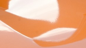 Imagen del frente y parrilla de una camioneta de color naranja de la marca Nissan.