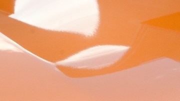 Imagen del frente y parrilla de una camioneta de color naranja de la marca Nissan.