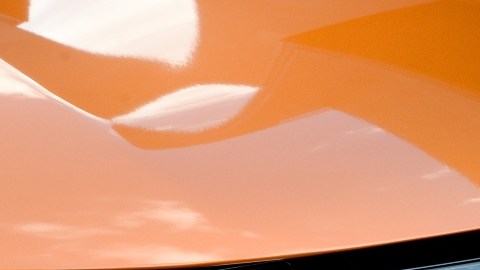 Imagen del frente y parrilla de una camioneta de color naranja de la marca Nissan.