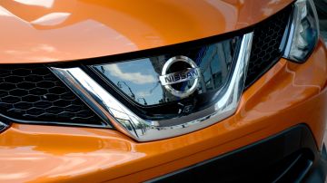 Imagen del frente y parrilla de una camioneta de color naranja de la marca Nissan.