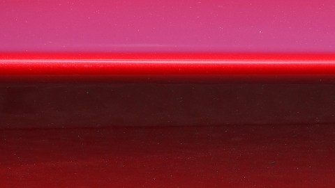 Imagen del logotipo de la marca Tesla colocado sobre un fondo de color rojo.