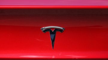 Imagen del logotipo de la marca Tesla colocado sobre un fondo de color rojo.
