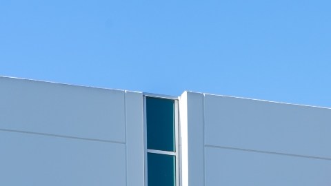 Imagen de un edificio con muros blancos en los que se ve el logotipo de la empresa Virgin Orbit en color rojo.