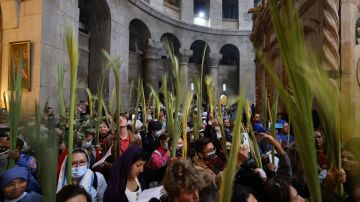 Worshippers carry palm branches as they circle the aedicule during the Palm Sunday procession at the Church of the Holy Sepulchre in Jerusalem's Old City, on April 10, 2022. - The ceremony is a landmark in the Roman Catholic calendar, marking the triumphant return of Christ to Jerusalem the week before his death, when a cheering crowd greeted him waving palm leaves. Palm Sunday marks the start of the most solemn week in the Christian calendar. (Photo by AHMAD GHARABLI / AFP) (Photo by AHMAD GHARABLI/AFP via Getty Images)