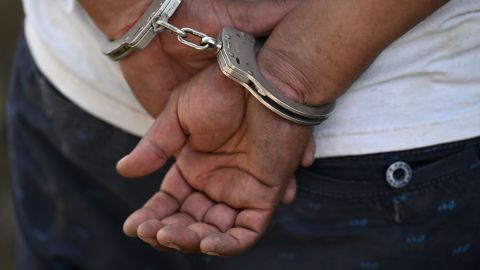 A man remains handcuffed after being detained by the police during an operation against gang members in Soyapango, El Salvador, on December 3, 2022. - Around 10,000 Salvadoran army troops and police officers surrounded the populous city of Soyapango, on the outskirts of capital San Salvador, as the government stepped up its fight against criminal gangs, President Nayib Bukele announced Saturday. (Photo by Marvin RECINOS / AFP) (Photo by MARVIN RECINOS/AFP via Getty Images)