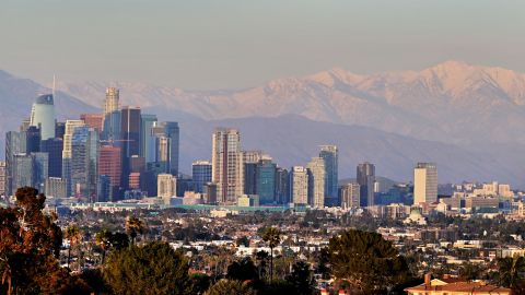 Snow-capped mountains are seen in the distance behind the downtown skyline on March 2, 2023 in Los Angeles, California where a new cold system brought hail and snow to unusually low elevations for the mountains in Southern California. (Photo by Frederic J. BROWN / AFP) (Photo by FREDERIC J. BROWN/AFP via Getty Images)