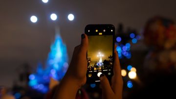 SHANGHAI, CHINA - JUNE 30: A girl takes photo of the night show of the Enchanted Storybook Castle at Shanghai Disneyland on June 30, 2022 in Shanghai, China. (Photo by Hu Chengwei/Getty Images)