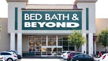 Imagen de una tienda de la marca Bed Bath & Beyond, con una marquesina de color verde y letras blancas, en medio de un estacionamiento.