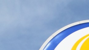 Imagen de un letrero de la marca Burger King, en colores azul, amarillo, rojo y blanco, en medio del cielo azul.