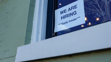 Imagen de un letrero de contratación pegado en la ventana de un negocio.