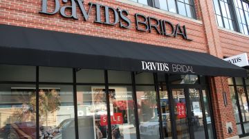 Imagen de una tienda de la marca David’s Bridal, en la que se ve una tienda con aparadores de cristal y una marquesina con letras de color negro.