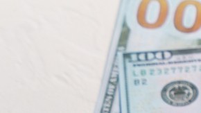 Imagen de un teléfono con el logotipo de Facebook en la pantalla y colocado sobre un montón de fajos de billetes.