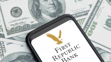 Imagen de un teléfono celular en cuya pantalla se ve el logotipo de First Republic Bank, y de varios billetes de $100 dólares.