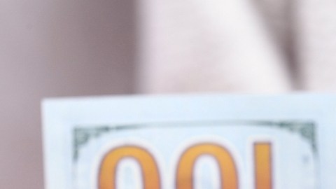 Imagen de una casa de manera en miniatura cubierta con varios billetes y una llave de color plateado.