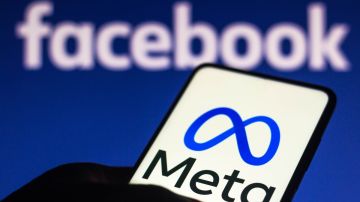 Imagen de un teléfono celular con el logotipo de Meta en la pantalla y en el fondo una pantalla azul con el logotipo de Facebook.