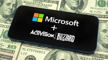Imagen de un teléfono celular que está sobre varios billetes y en la pantalla se ve un logotipo de Microsoft y de Activision.
