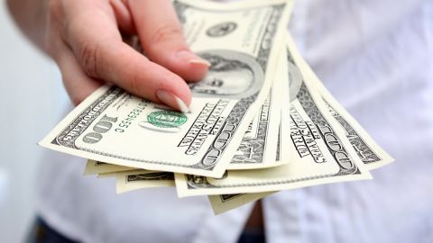 Imagen de una persona que entrega billetes con la mano.
