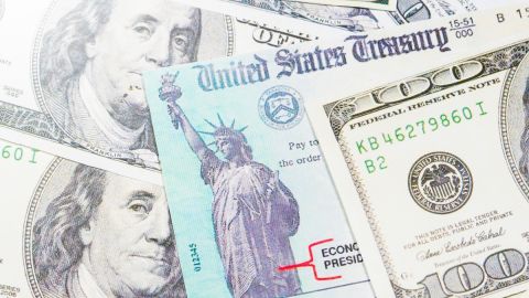Imagen de un cheque de reembolso de impuestos, en medio de varios billetes.