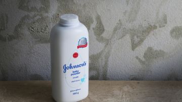 Imagen de una botella de talco para bebé de la marca Johnson & Johnson, colocada sobre una superficie de piedra.