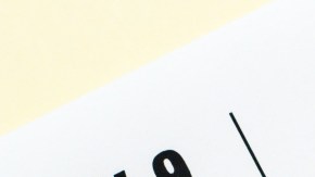 Imagen de un post-it de color amarillo con la frase Tax Day en color azul, sobre un formulario de impuestos y unos clips.