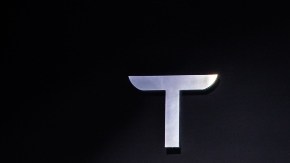 Imagen de dos vehículos de Tesla, uno en color azul y otro en rojo, en medio de una sala de exhibiciones.